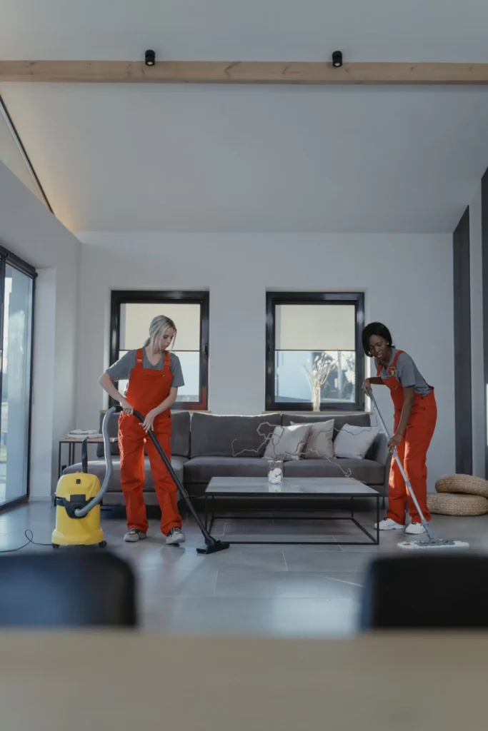 Two cleaners vacuuming and mopping a living room